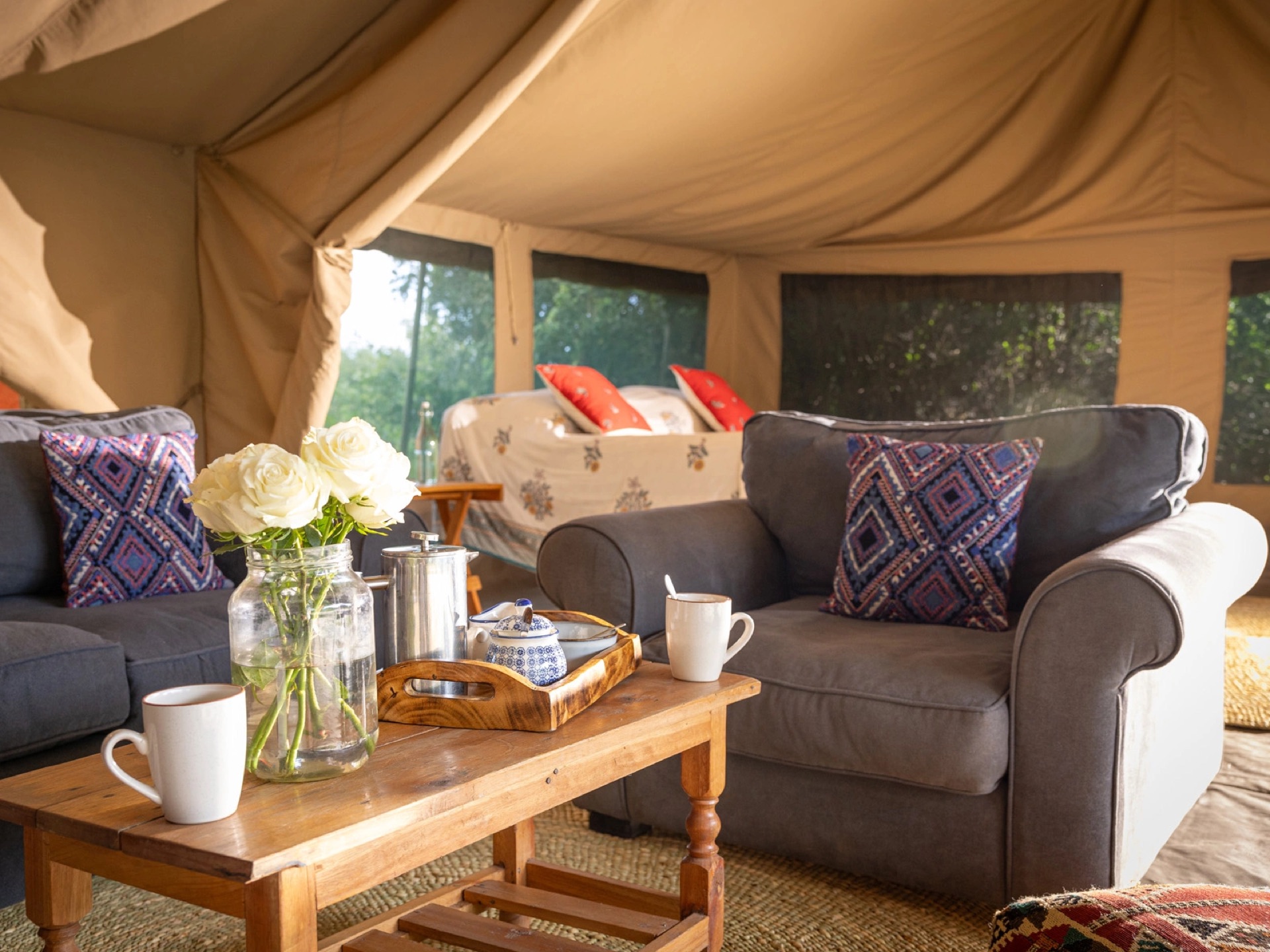 A tented sitting area with armchairs, a tea tray and flowers
