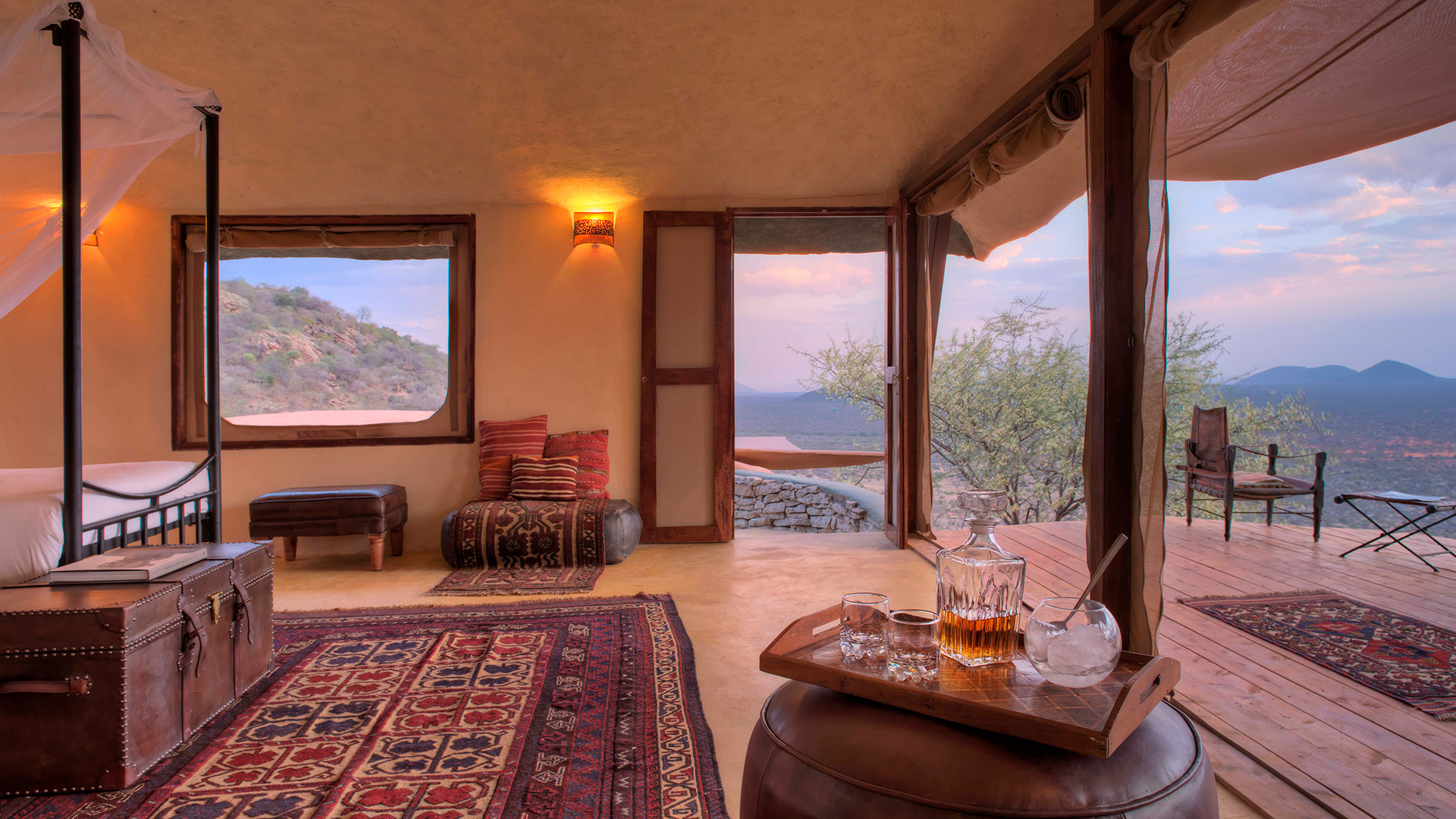A villa bedroom opening onto a veranda with a view over the hills